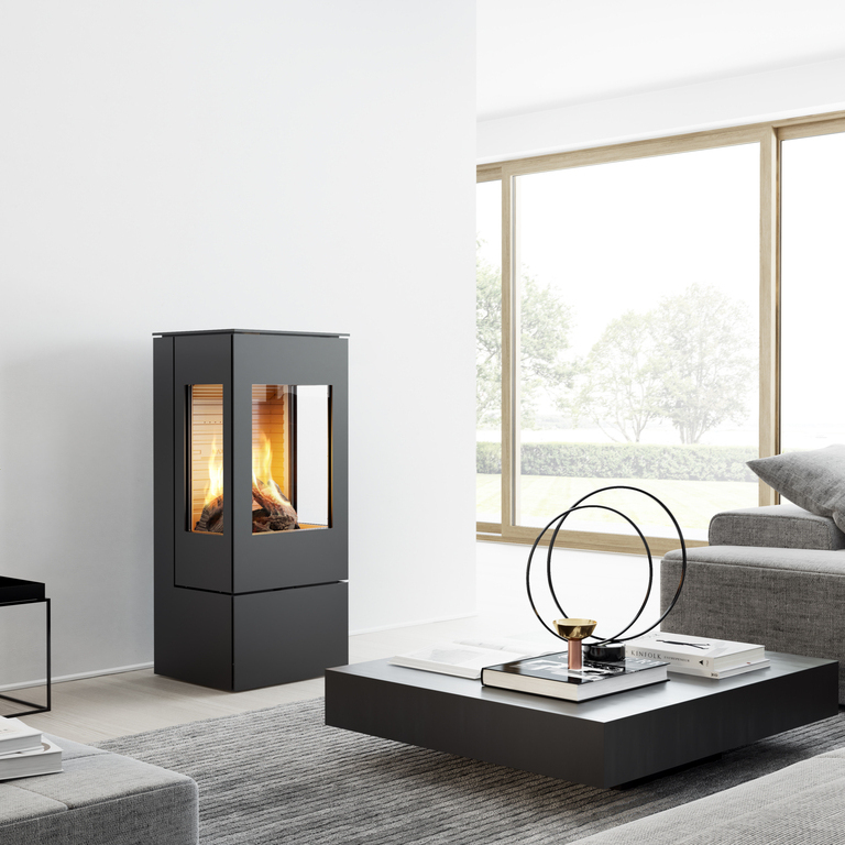 Gas stove NEXO 100 in black with steel door and two side windows in a modern, bright living room