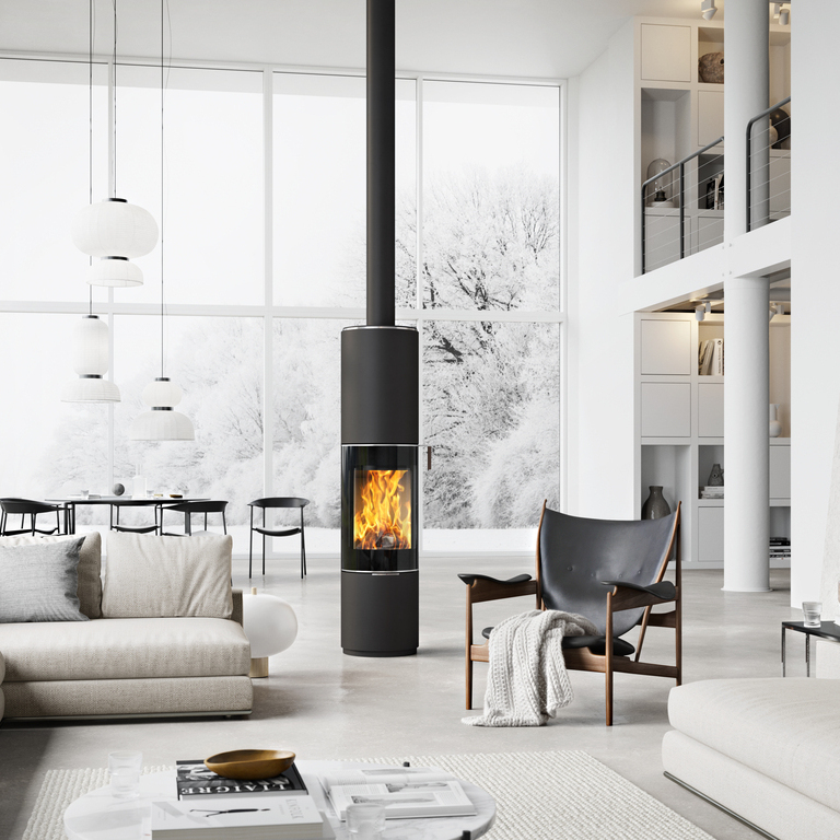 Wood stove PILAR in black with glass door as a rotating, round stove in the centre of a huge living room in Scandi style