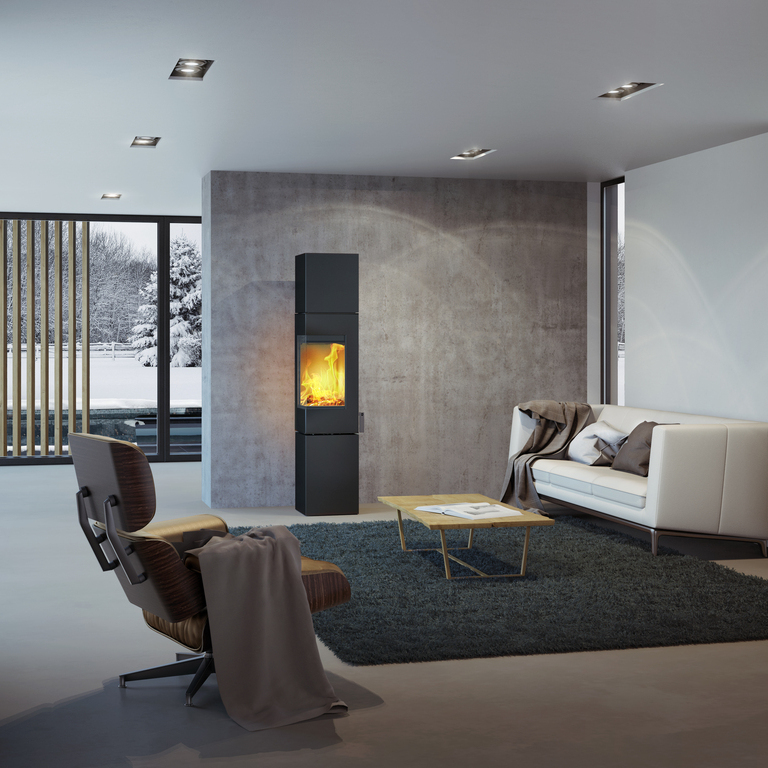 Wood stove Q-BE XL in black with steel door in a modern living room surrounded by a beautiful snowy landscape