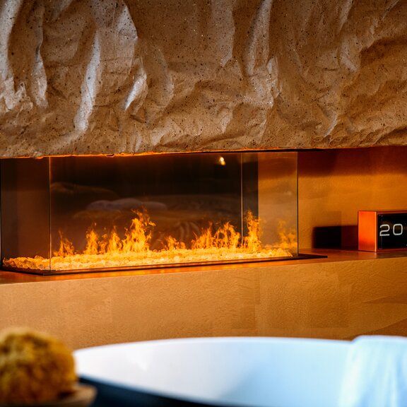 Elektrokamin e-Matrix Linear 1050-400 dreiseitig an orangener Wand mit Steinelementen und Badewanne