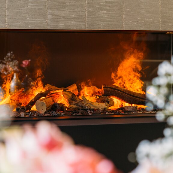 3-sided electric fireplace e-Matrix Linear 1300/400 from Dimplex built into a stone wall with floral decoration