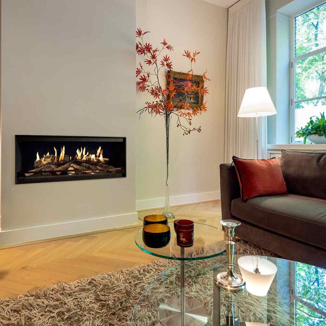 The E-One 100 Front electric fireplace installed in the living room of a country house with a white wall.