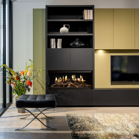 Il caminetto elettrico E-One 100 Front nel soggiorno come parte di una credenza verde con televisione integrata.
