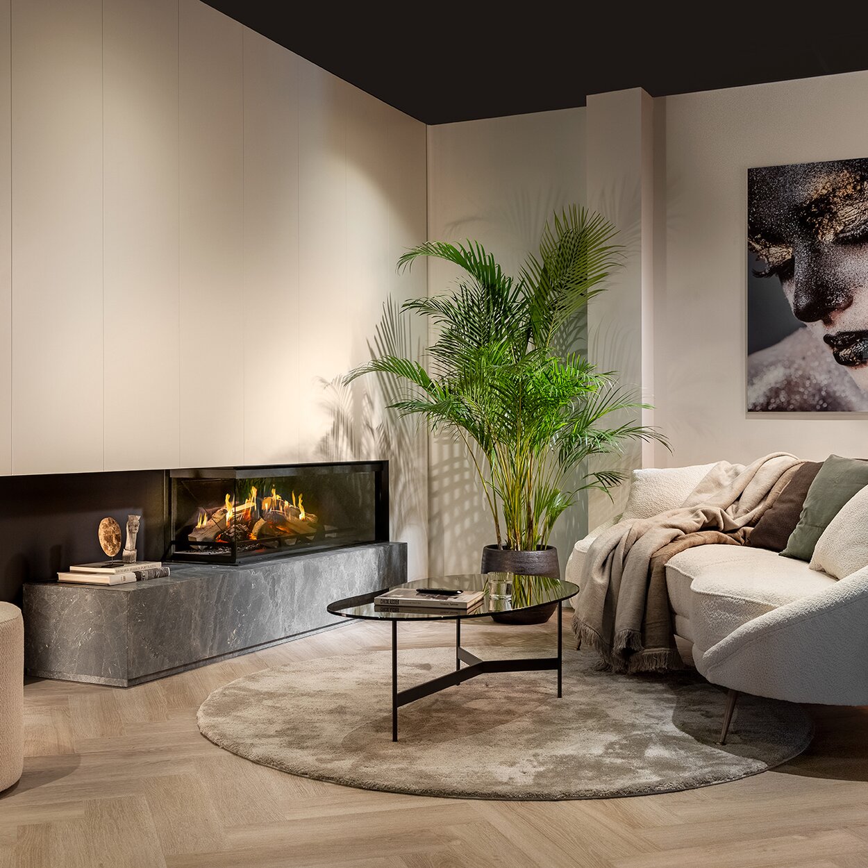 Le foyer électrique bi-face E-One 130 C encastré dans un salon blanc moderne avec canapé.