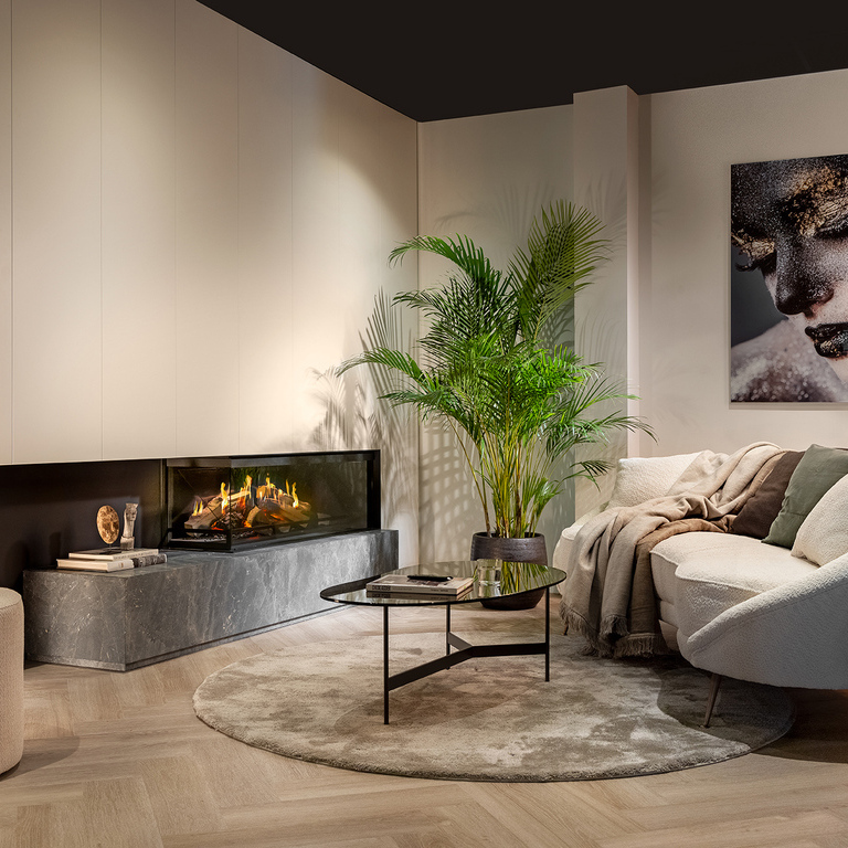 Le foyer électrique bi-face E-One 130 C encastré dans un salon blanc moderne avec canapé.