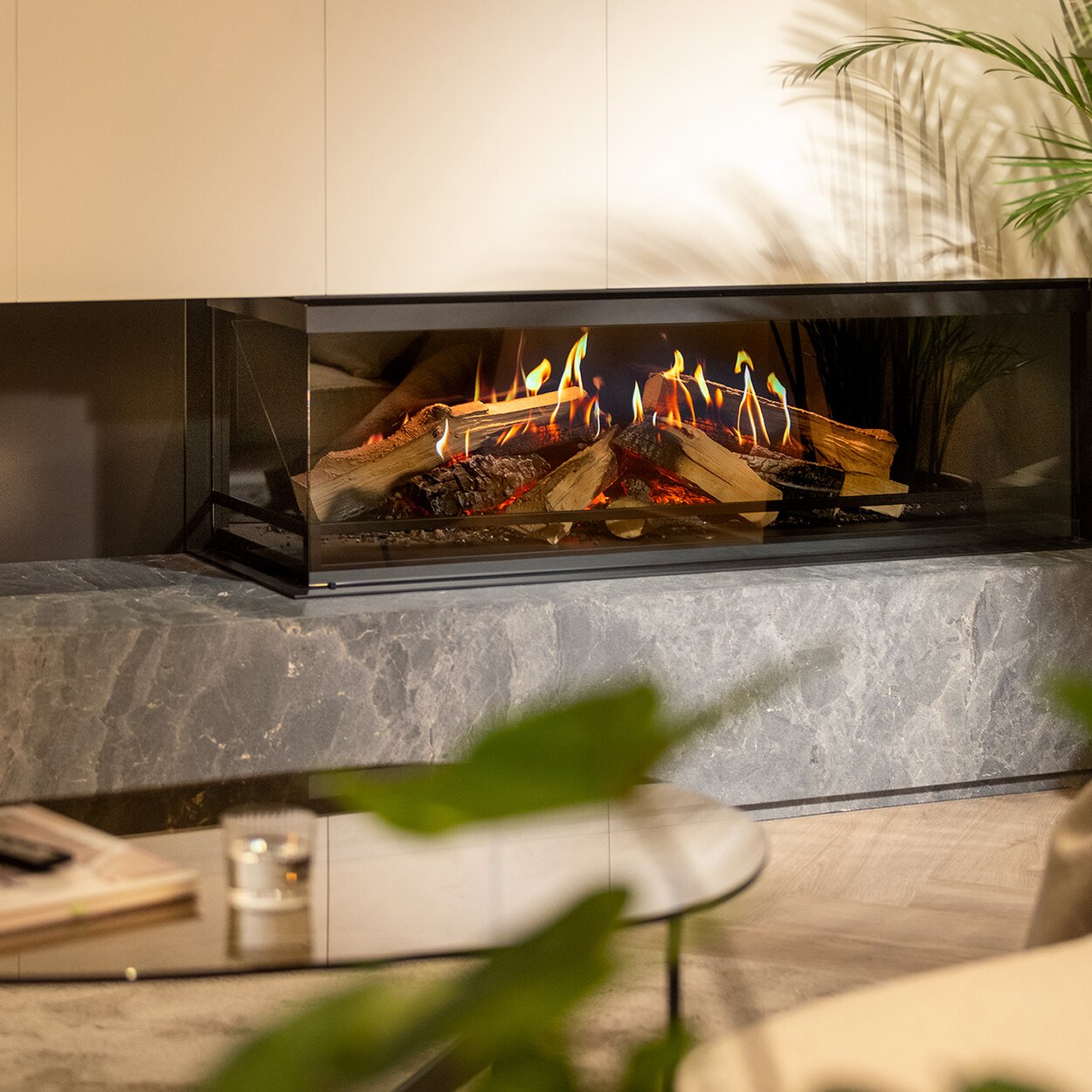 2-sided electric fireplace E-One 130 C in a cosy living room with sofa and glass table.