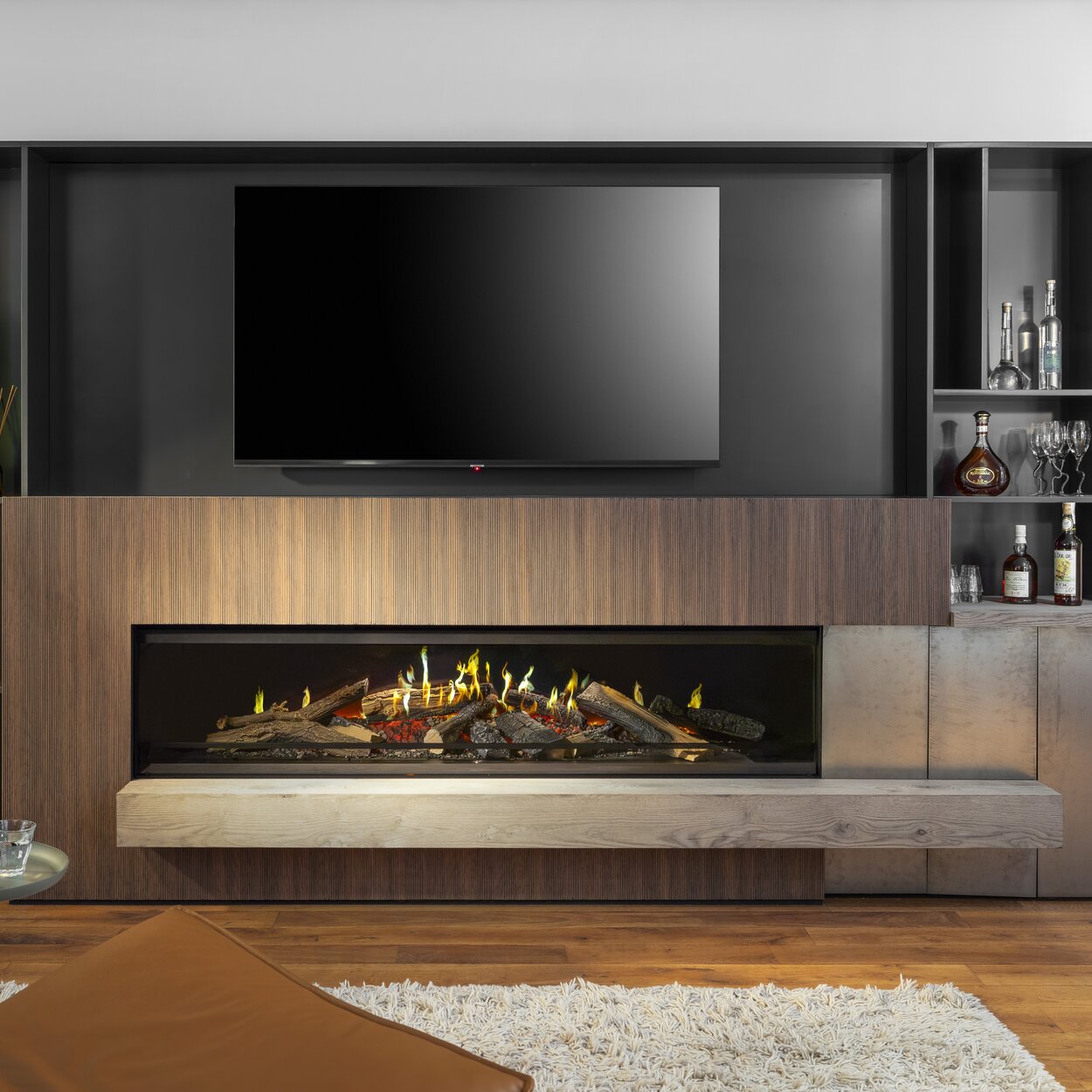 The widest electric fireplace E-One 190 F from Kalfire built into a wooden sideboard with TV and drawers.