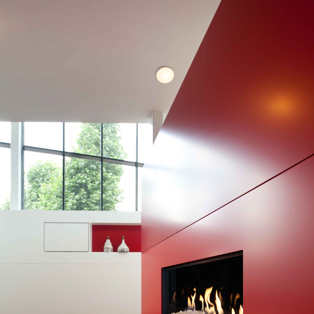 Gas fireplace G100/41F by Kalfire with white stones in the firebox built into a red wall