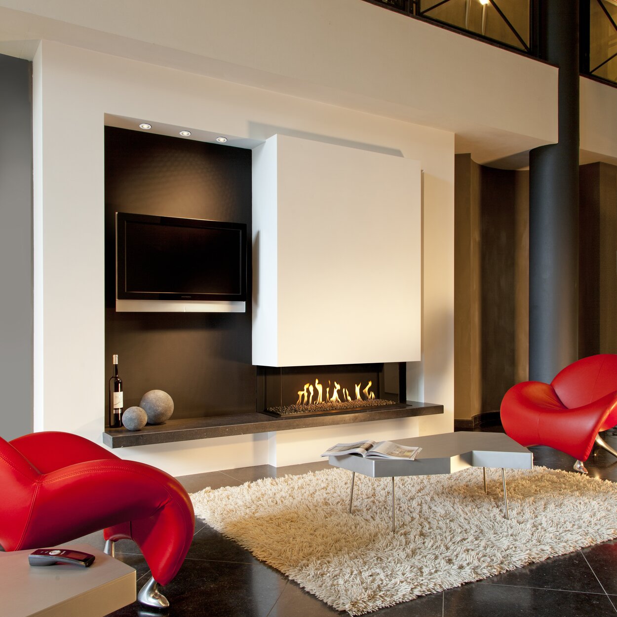 Gas-Kamin G110/37S dreiseitig mit Steinen im Brennraum in grossem Wohnraum mit roten Sesseln 