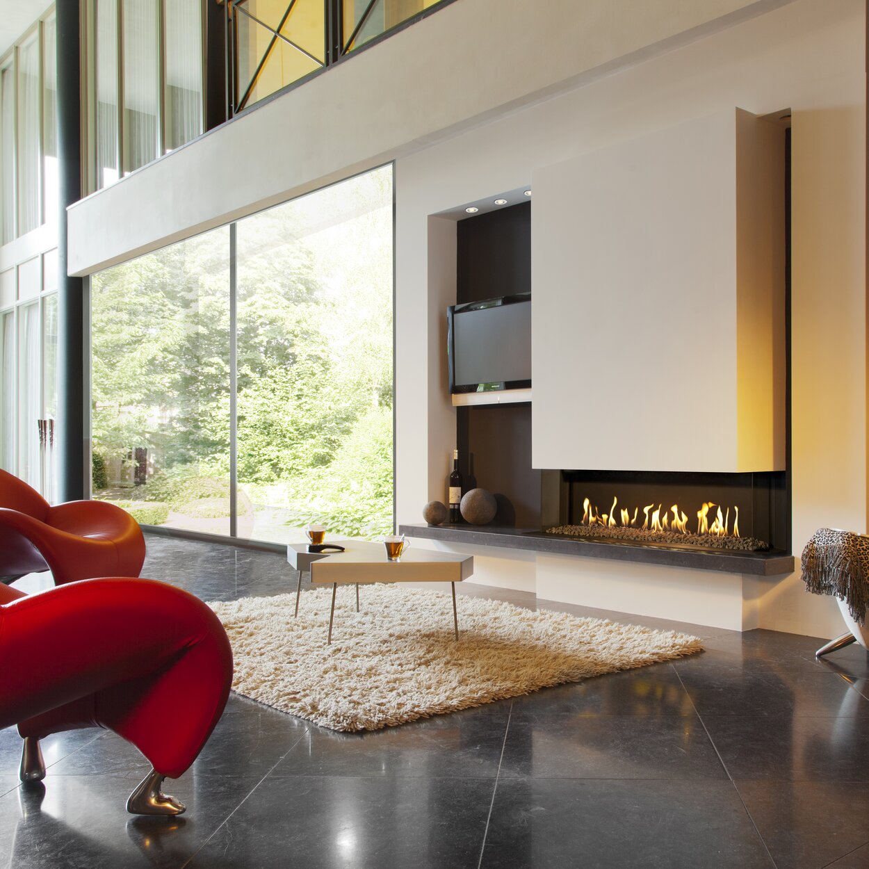 Gas fireplace G110/37S 3-sided by Kalfire in large living room with red armchairs 