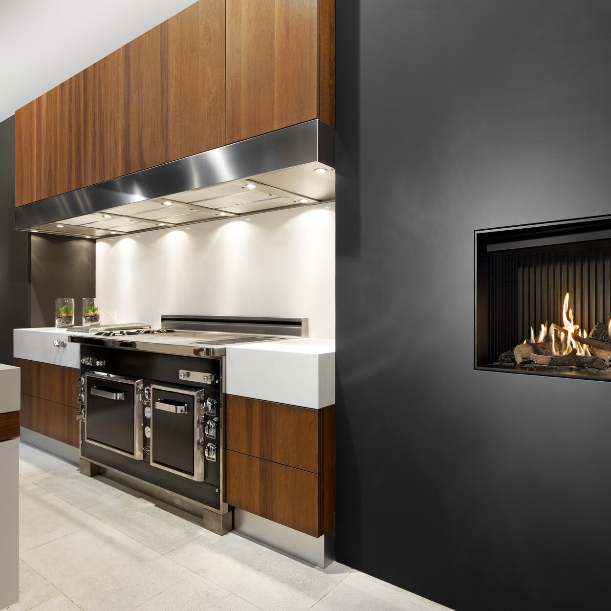 Camino a gas G60/48F versione frontale integrato nella parete nera della cucina con elementi in legno