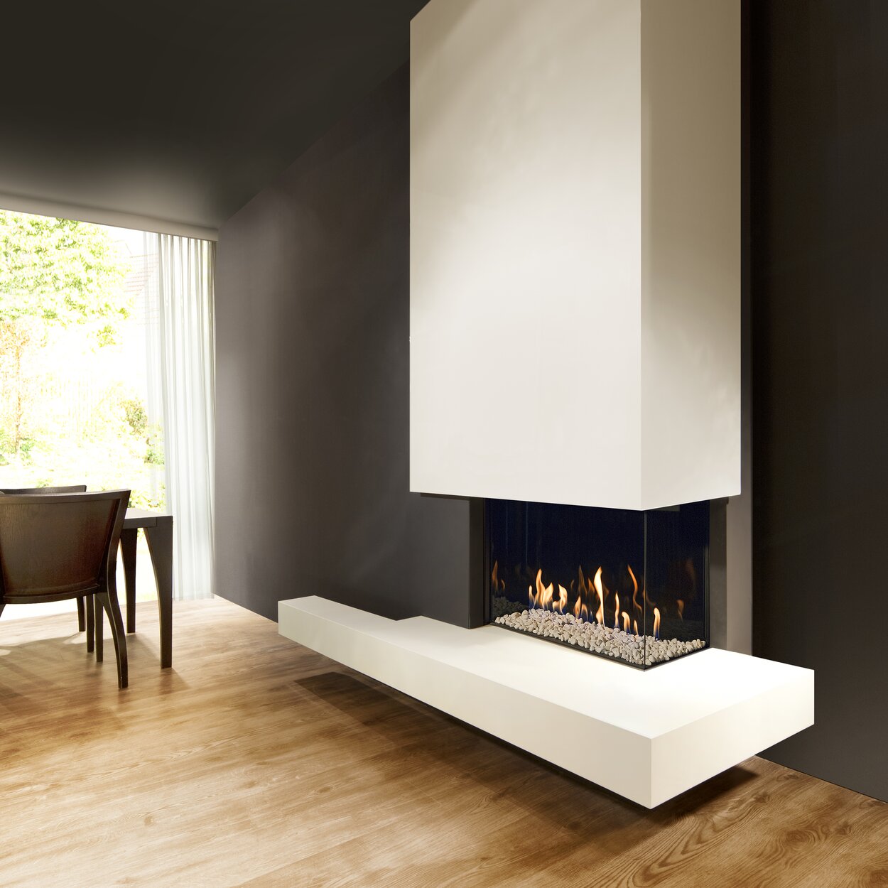Gas fireplace G65/44C corner version on a white base unit and with white panelling on a dark wall in a modern living room