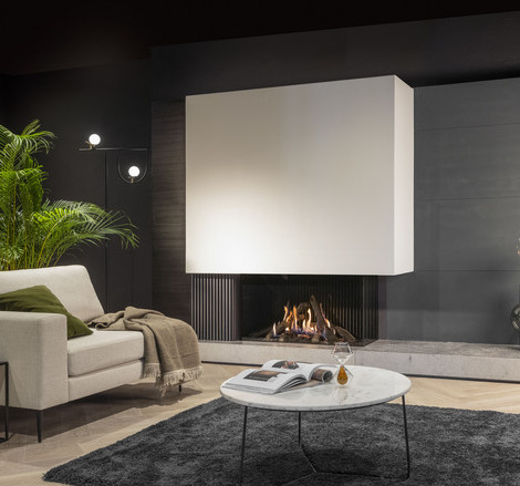 Gas-Kamin Gi1110/55C in Wohnraum mit weisser und grauer Verkleidung, grauem Sofa mit Kissen und Decke, Holzboden mit schwarzem Teppich