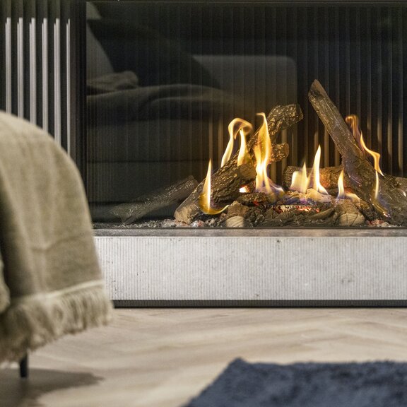 Camino a gas Gi110/55C: primo piano frontale del focolare con rivestimento interno di design e ciocchi