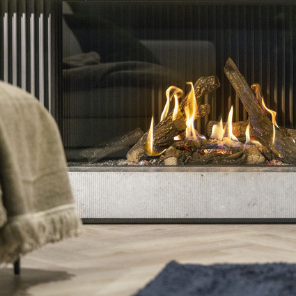 Camino a gas Gi110/55C: primo piano frontale del focolare con rivestimento interno di design e ciocchi