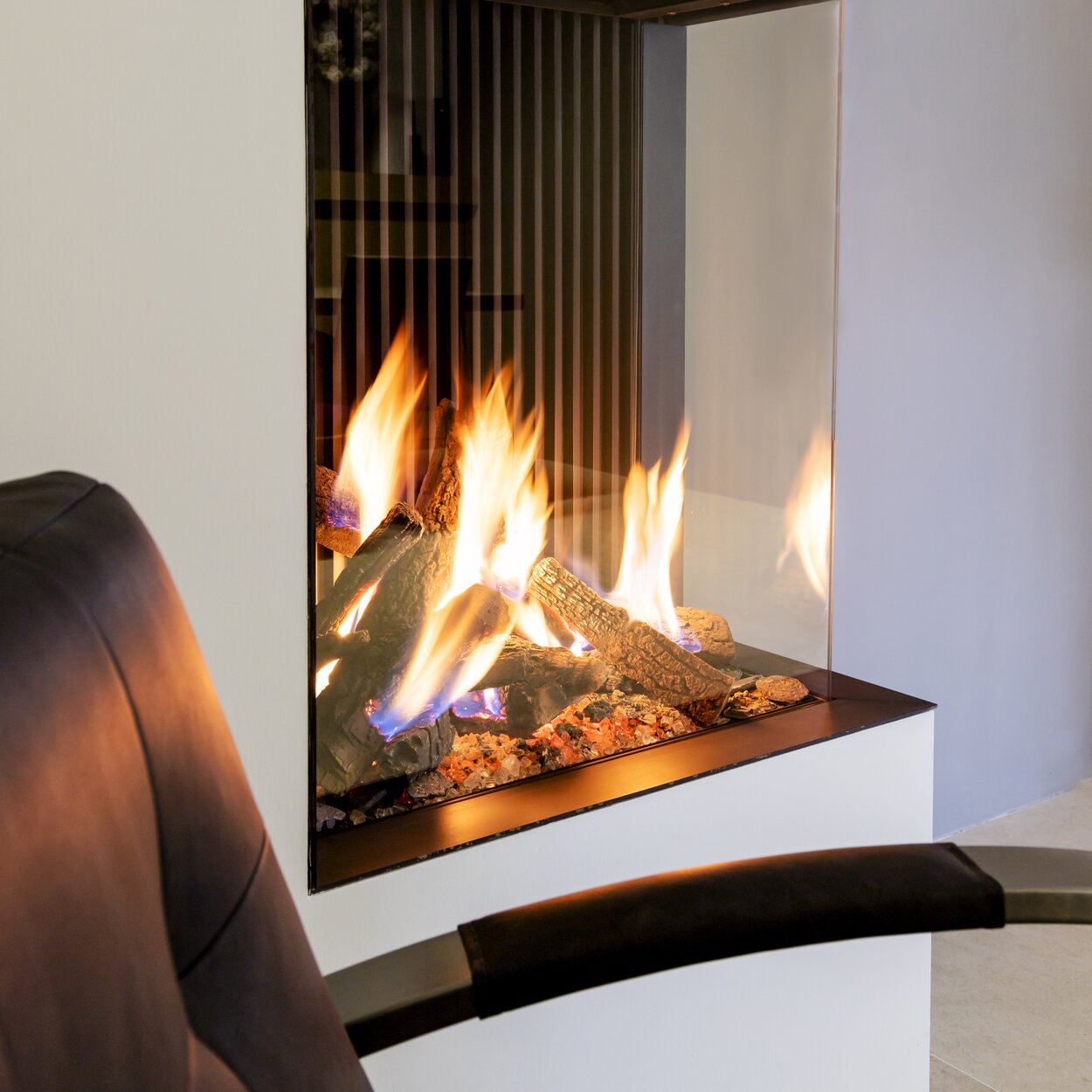 Gas fireplace GP65/75C corner version with white panelling and ceramic wood logs