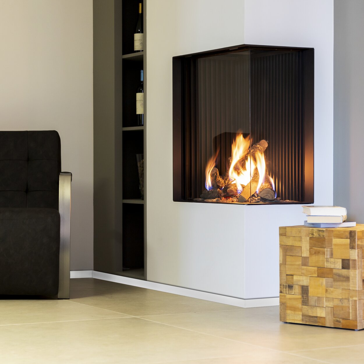 Corner variant gas fireplace GP65/75C with white panelling in the living room with shelf and armchair