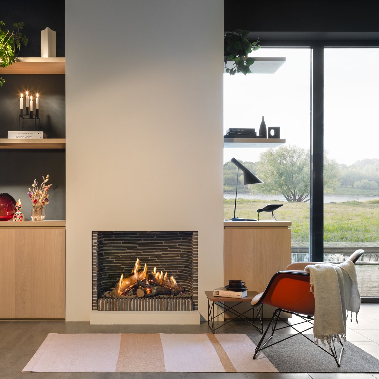 Gas fireplace GP75/59F front in a simple living room with large windows and a view of the green landscape and lake