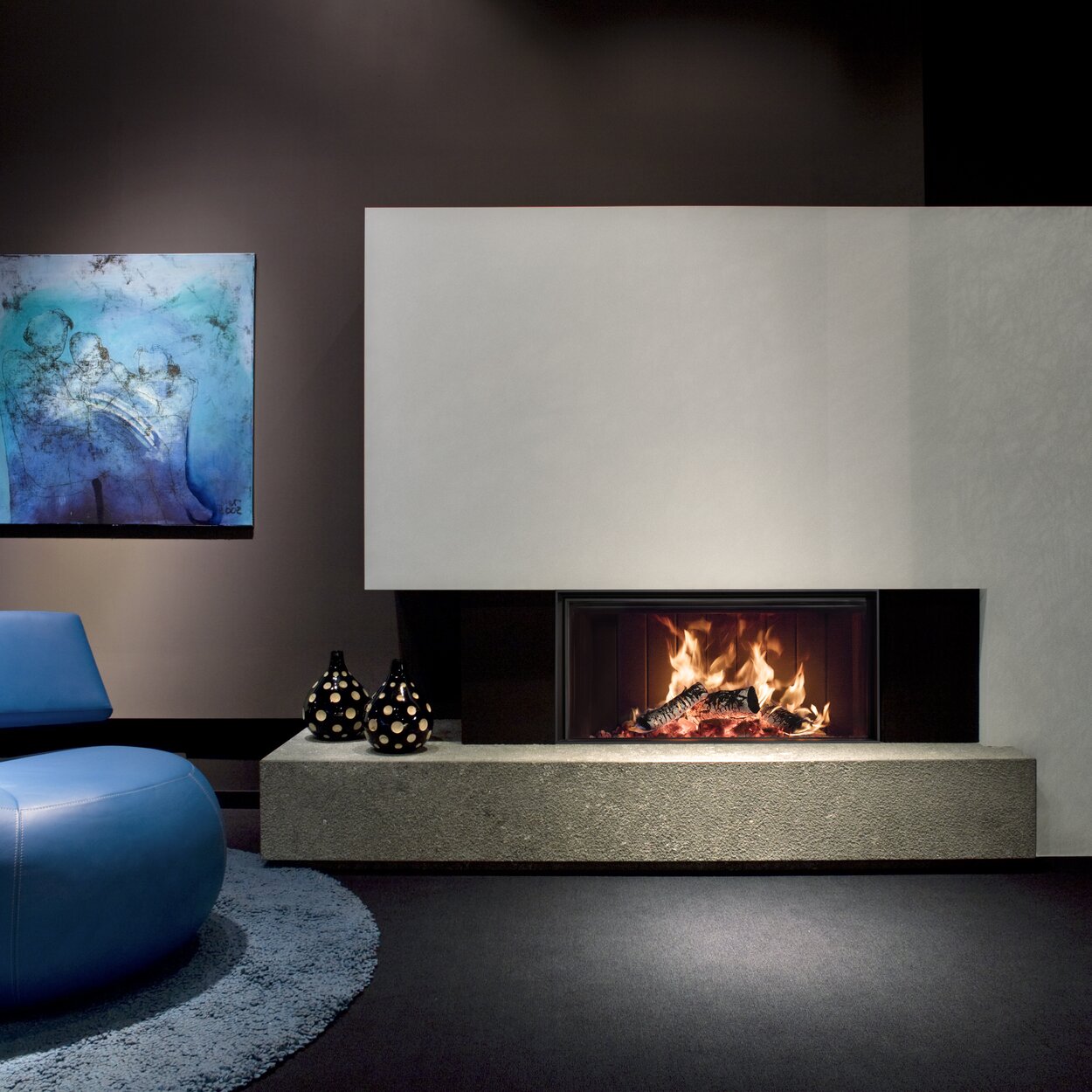 Camino a legna W105/47F di Kalfire in versione frontale in un elegante soggiorno con pareti marrone scuro e mobili blu
