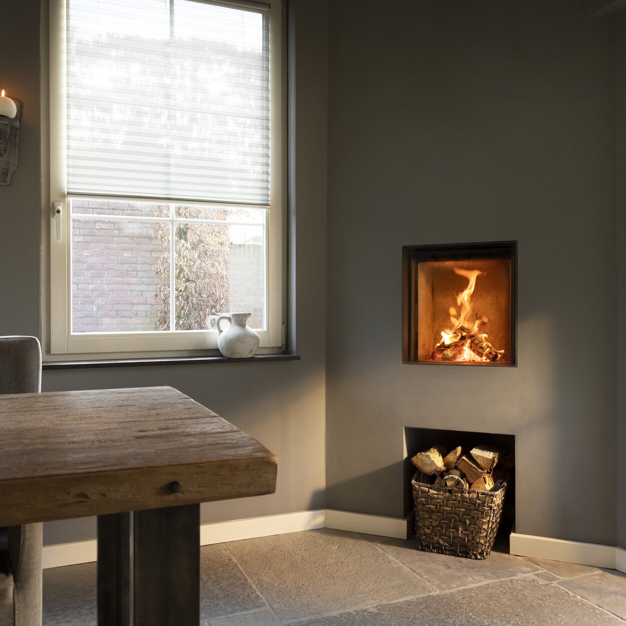 Wood fireplace W45/48F by Kalfire in front version as a compact fireplace in a grey wall corner with practical compartment for wood logs