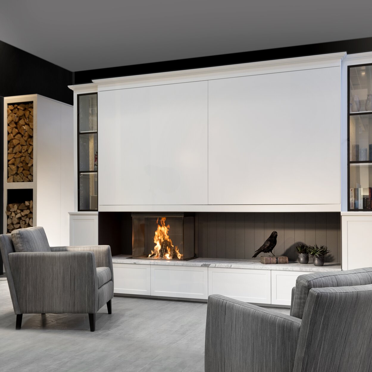 Wood fireplace W66/48S by Kalfire with 3-sided viewing panels built directly into white furniture in a lounge in grey tones