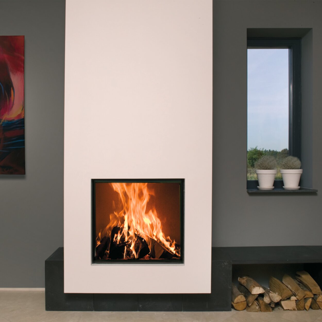 Wood fireplace W71/62F from Kalfire integrated in a white wall with black side bench and practical shelf for logs