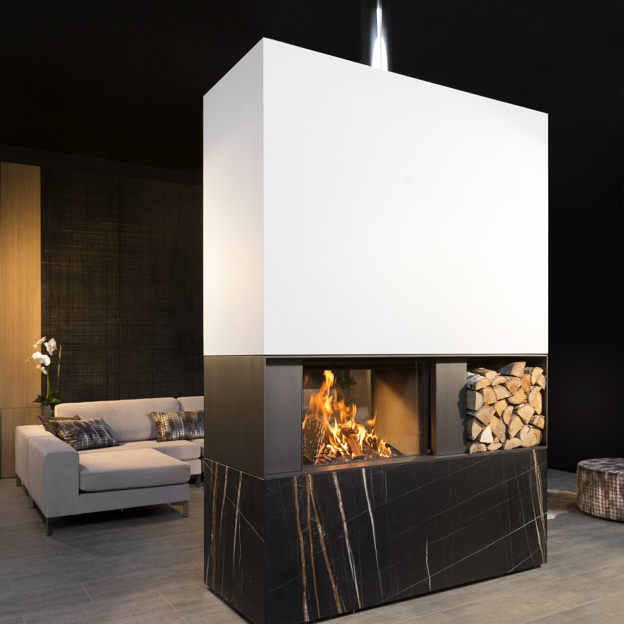 Camino a legna W80/52T di Kalfire come divisorio per ambienti con pratico contenitore di legna integrato in un soggiorno moderno