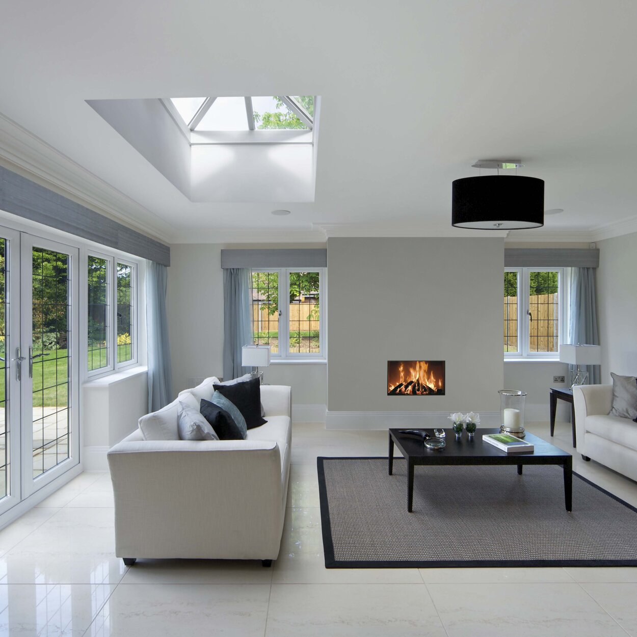 Holz-Kamin W85/40F von Kalfire in einem modernen, hellen Wohnraum mit Möblierung in Weiss und Schwarz